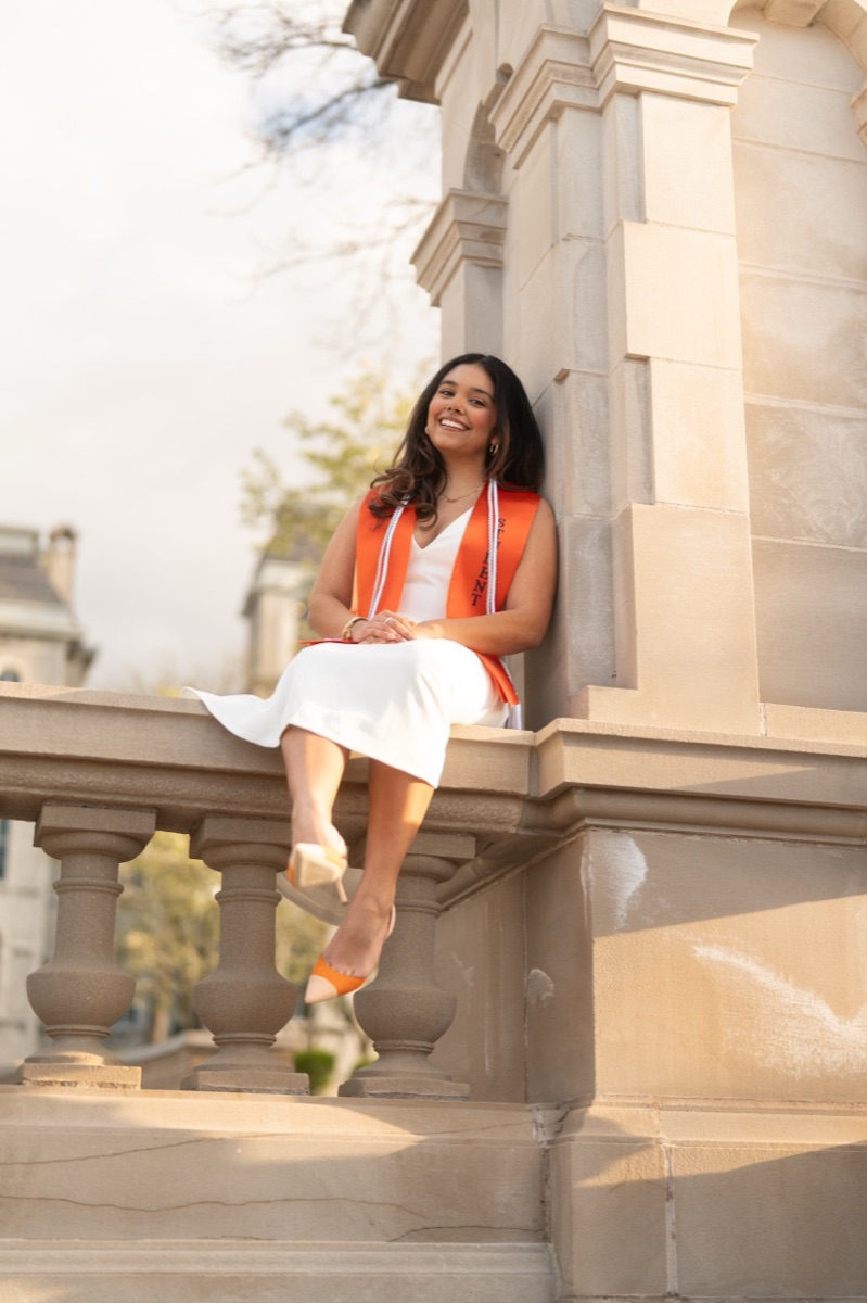 Senior portrait in warm golden-hour light on a stone balustrade